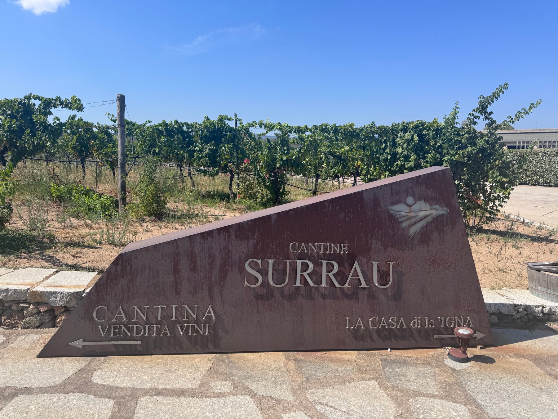 The weathered metal Cantine Surrau sign beside the vineyard