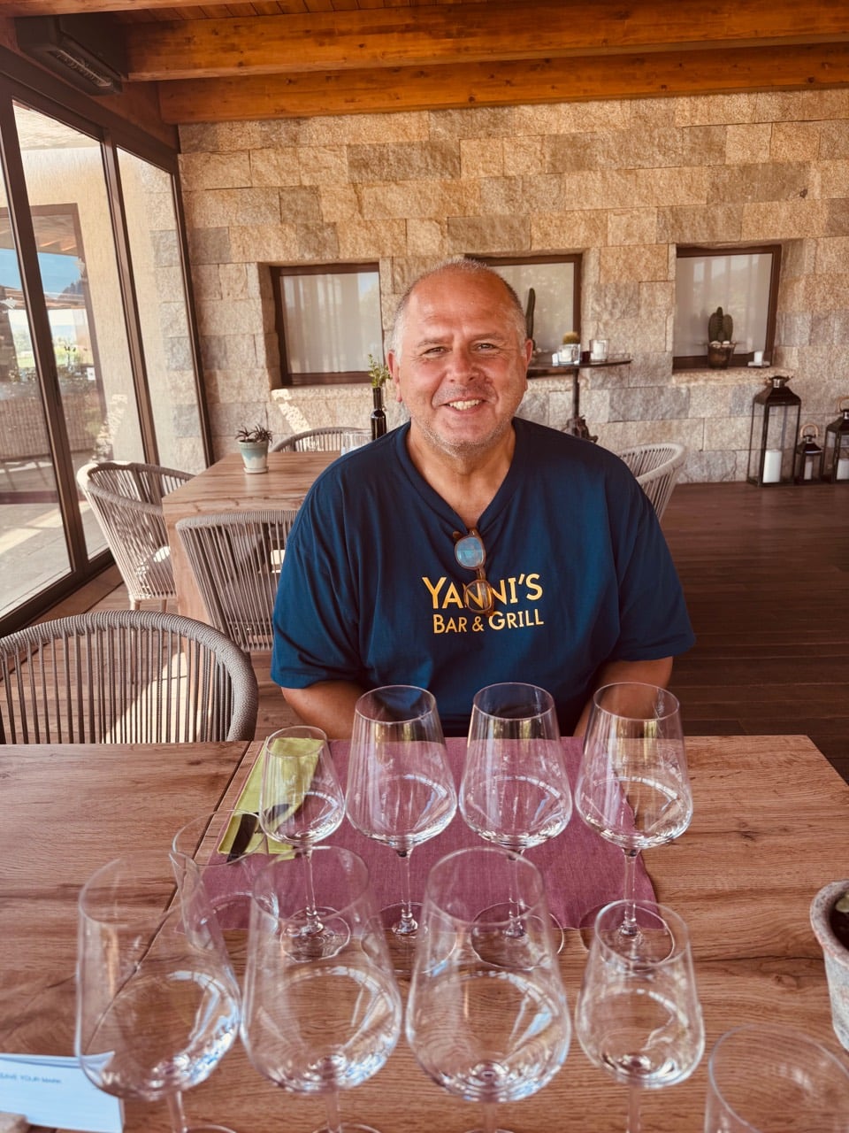 Yanni smiling behind a full flight of empty tasting glasses