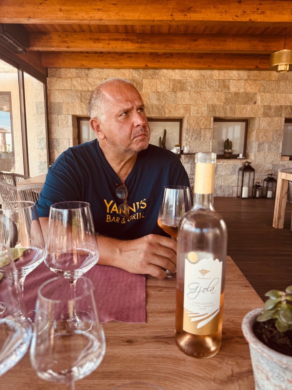 Yanni considering a glass beside a bottle of Surrau rosato
