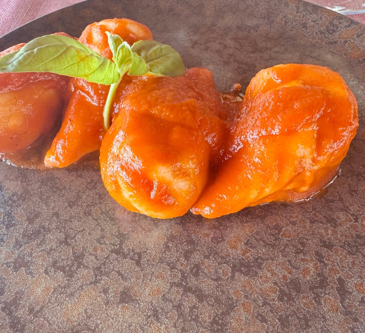 The first plated course in a bright tomato sauce with basil