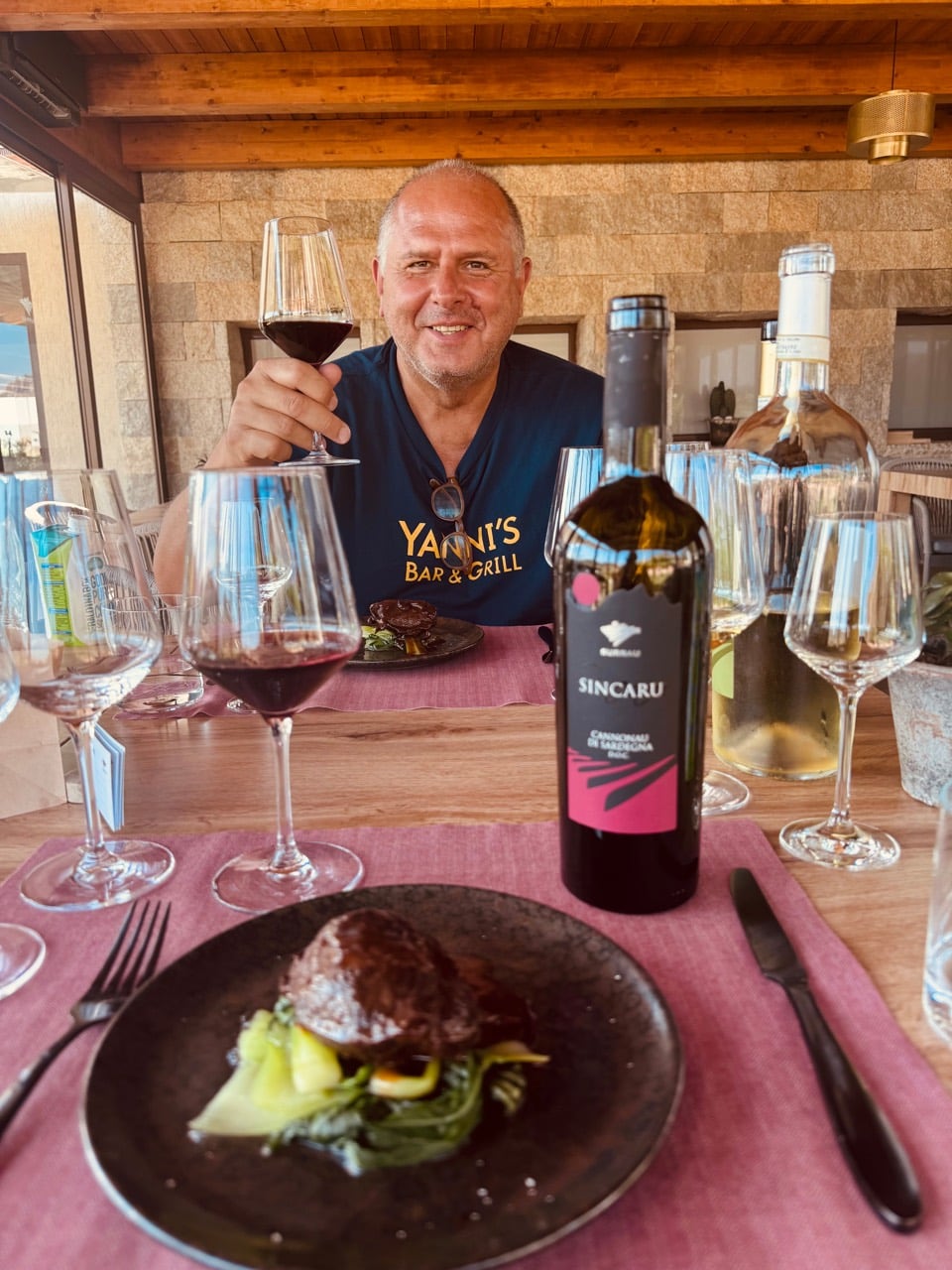 Yanni raising a glass of Cannonau over a plated course paired with Sincaru