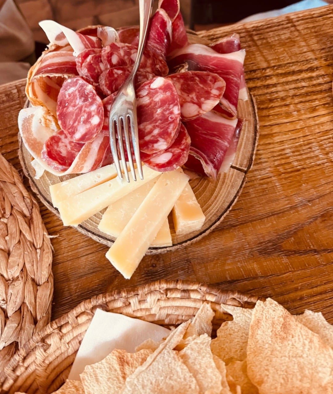 Local cured meats, aged cheese and crisp Sardinian bread on a wooden table
