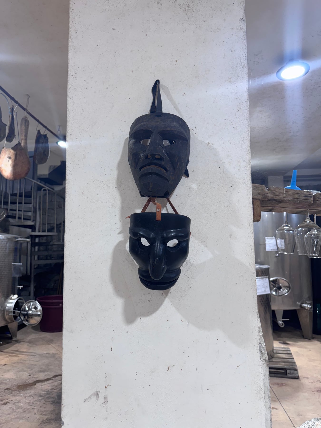 Traditional dark Mamoiada masks hanging inside the working winery