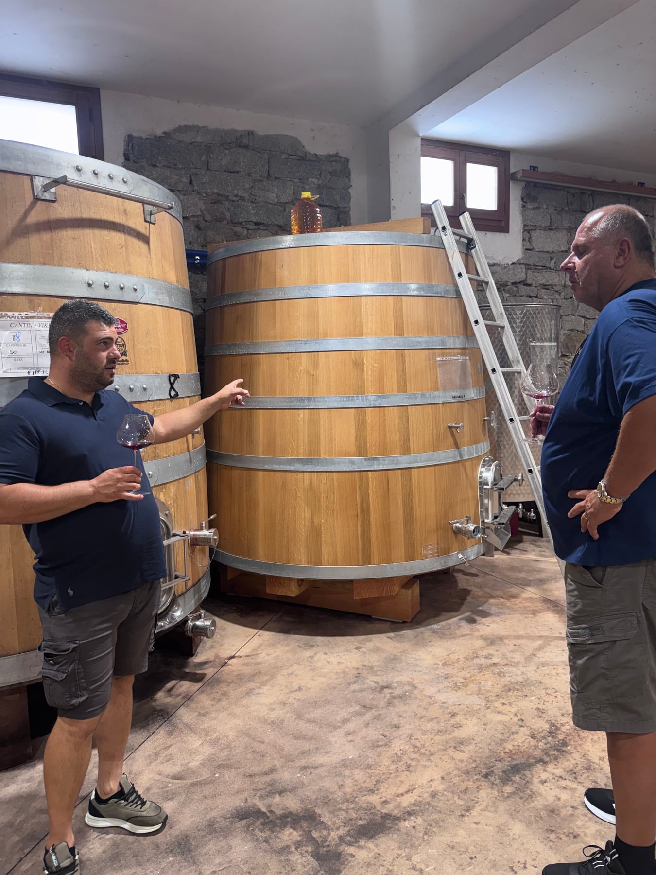 Simone and Yanni talking beside large wooden fermentation vats