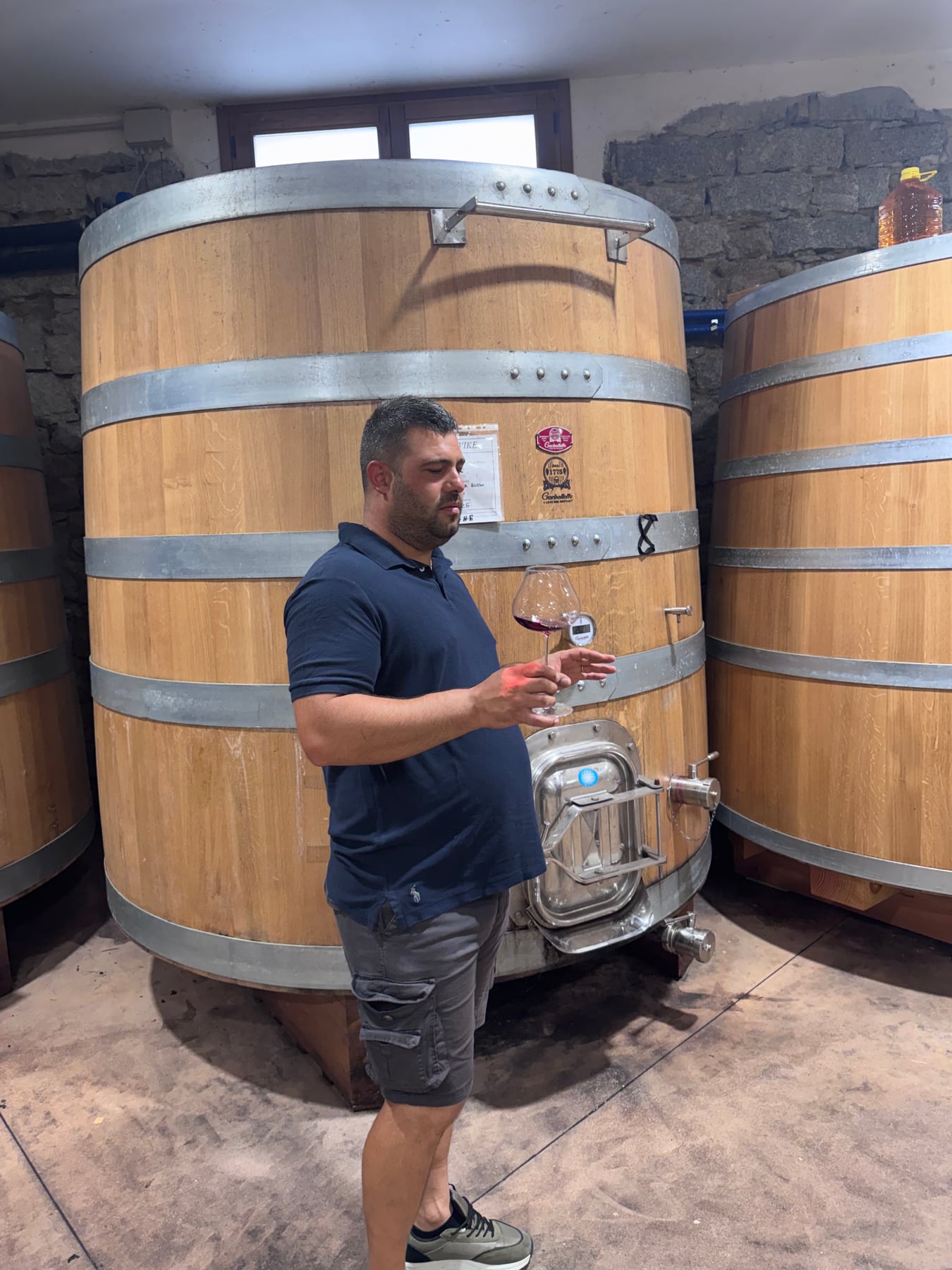 Simone tasting beside a large wooden fermentation vat